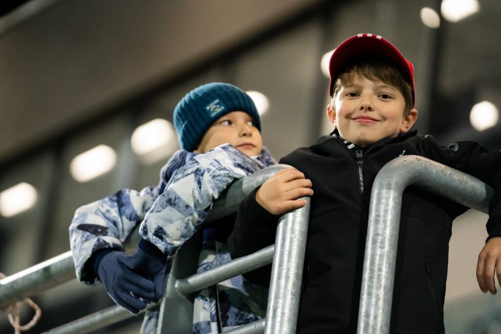 Młodzi kibice oglądają mecz z trybuny. 23 października 2026.